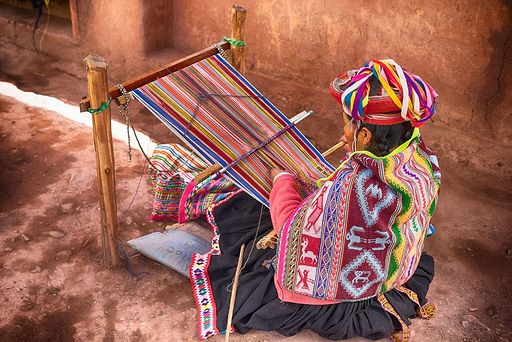 a woman weaves a colorful pattern using a machine